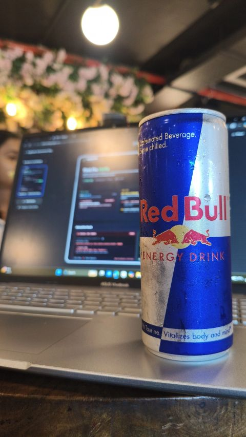 Chilled can of Red Bull on laptop keyboard during coding session