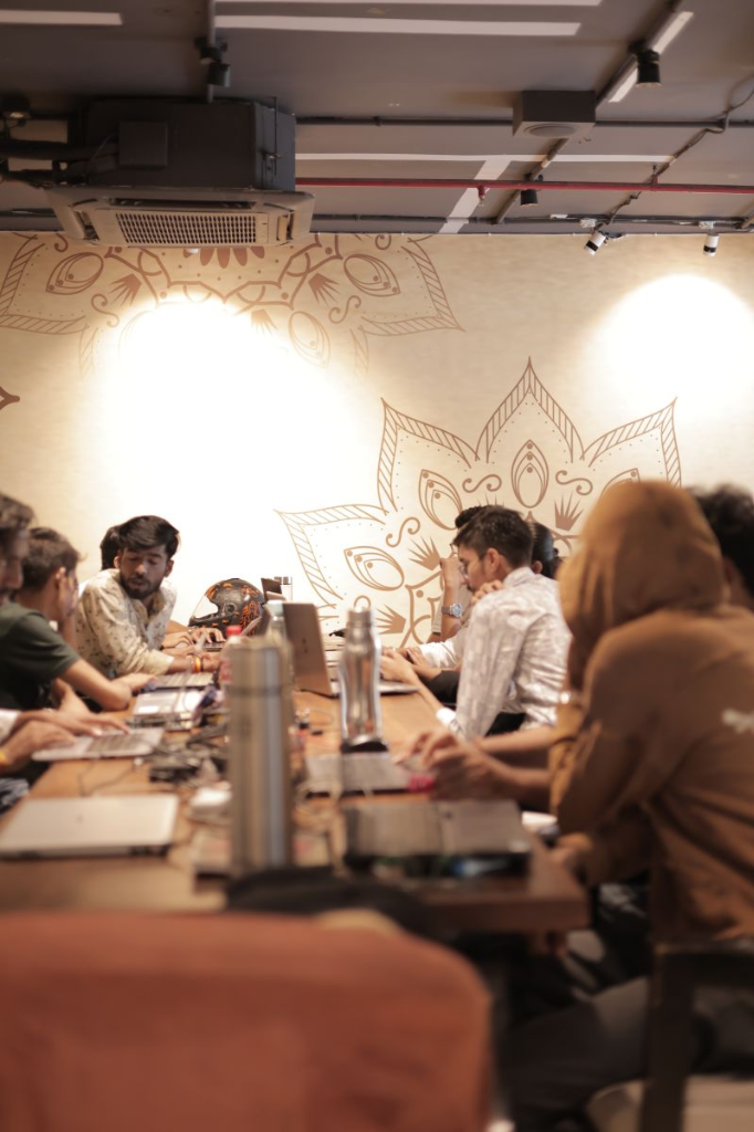 Hackers lined along wooden table coding intensely under mandala lights